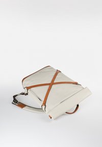 Hellbeiger Rolltop-Rucksack mit braunen Lederriemen und verstellbarem Schultergurt, flach auf einer weißen Oberfläche liegend.