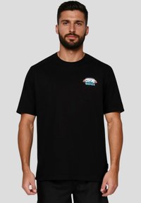 Camiseta negra de manga corta hecha de algodón. En la parte delantera presenta un gráfico colorido con el texto "BUENOS AMIGOS" sobre personajes ilustrados.