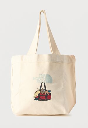 Crèmekleurige totebag met het The North Face-logo en een illustratie van drie katten die spelen rond een rode tas aan de voorkant.