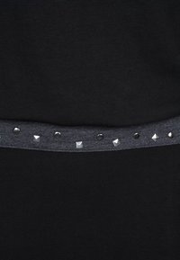 Czarna odzież z szarym pasem ozdobionym okrągłymi i piramidalnymi metalowymi ćwiekami, które dodają tekstury i detalu.