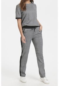 Conjunto atlético a cuadros grises que incluye una camiseta de manga corta con borde negro y pantalones a juego con franjas laterales y una cintura ajustable con cordón.