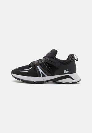 Scarpe da ginnastica nere realizzate in mesh e materiale sintetico, con strisce riflettenti, lacci elastici e una suola bianca con un motivo a texture.