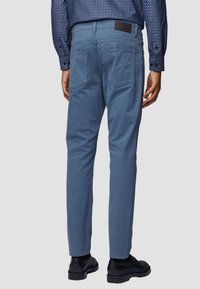 Ljusblå slim-fit byxor i bomull, med bakfickor, en läderetikett på midjebandet och en mjuk textur.