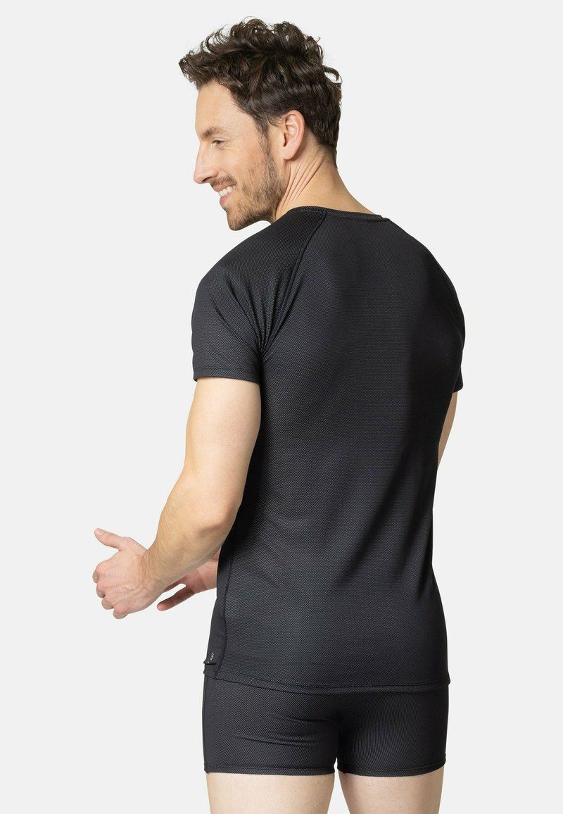 Czarna koszulka sportowa z teksturowanym wzorem, krótkimi rękawami i dopasowanym krojem, w zestawie z dopasowanymi czarnymi szortami.