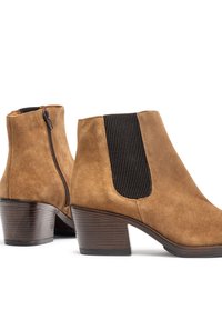 Bottines en daim marron avec panneaux élastiques sur les côtés, fermeture éclair et talon empilé avec une finition texturée.