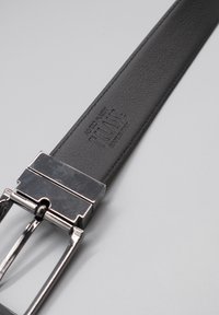 Cintura in pelle nera caratterizzata da una texture liscia, fibbia metallica con finitura lucida e logo del marchio impresso con la scritta "TILANTE MADE IN ITALY".