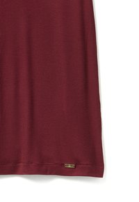 Burgundská žebrovaná šaty s přiléhavým střihem, na spodním okraji se nachází malý kovový štítek značky, který přidává detail a kontrast textur.