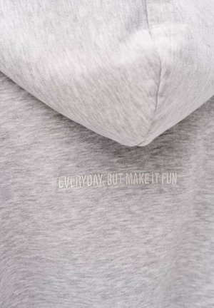 Jasnoszary materiał bluzy z kapturem z wyhaftowanym napisem „EVERYDAY, BUT MAKE IT FUN” w kolorze dopasowanym do tkaniny, umieszczonym w okolicy klatki piersiowej.