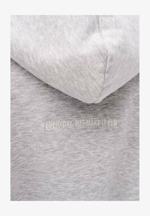 Jasnoszary materiał bluzy z kapturem z wyhaftowanym napisem „EVERYDAY, BUT MAKE IT FUN” w kolorze dopasowanym do tkaniny, umieszczonym w okolicy klatki piersiowej.