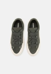 Zapatillas de ante verde con suelas de goma blanca. Presenta puntera redonda, cordones planos y costuras blancas contrastantes. Logo visible en la plantilla.