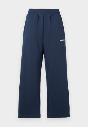 Pantaloni de trening bleu închis, realizați dintr-un material moale, având talie elastică, buzunare laterale și un accent subtil cu un logo alb.