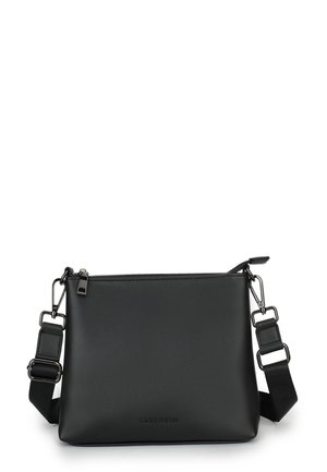 Black crossbody bag made of smooth faux leather. Features a zip closure, adjustable strap, and subtle logo. Minimalist rectangular design.