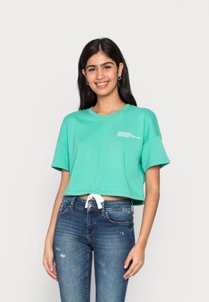 Cropped, light green t-shirt made of cotton. Features a round neckline, short sleeves, and a front knot detail. White text on the chest.