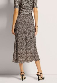 Leopardenmuster Midi-Kleid aus weichem Stoff, mit einer taillierten Taille und einem ausgestellten Rock. Passend dazu schwarze High-Heels.