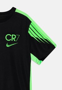 Camiseta deportiva negra con mangas cortas de malla verde, que presenta el logo de CR7 y el swoosh de Nike en verde brillante en el pecho y el hombro.
