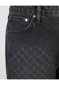 Jean en denim foncé avec une texture à motif subtil, accessoires en métal argenté et un design classique à 5 poches.