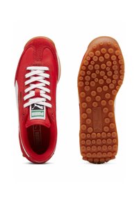 Röda sportskor med vita detaljer, med ett överdel i tyg och gummi, texturerad gummisula och vita snörningar. Puma-logotyp på tungan.