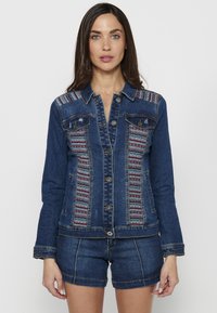 Denim jakna z večbarvnimi tkanimi detajli na ramenskih delih, z gumbnim zapiranjem, dvema sprednjima žepoma in prileganjem.