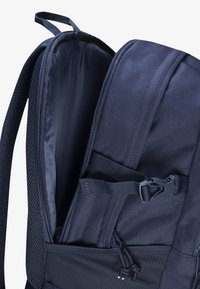 Marinblå ryggsäck med ett rymligt, fodrat innertyg, nätfack och justerbara remmar. Inkluderar öglor och beslag för att fästa tillbehör.