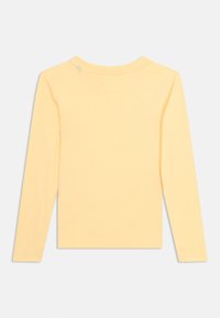 Απλό ανοιχτό κίτρινο πουκάμισο με μακριά μανίκια, εμφανιζόμενο από πίσω σε λευκό φόντο, με μια μικρή αχνή κηλίδα κοντά στον λαιμό.