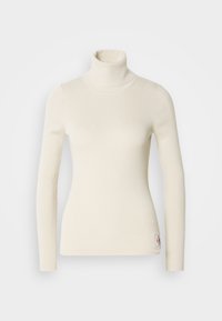 Pull col roulé en maille côtelée couleur crème avec manches longues et petit patch logo près de l'ourlet sur fond blanc.