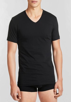 T-shirt nera a maniche corte con scollo a V, realizzata in tessuto morbido, vestibilità slim, con una consistenza liscia e cuciture pulite, indossata con pantaloni corti neri.