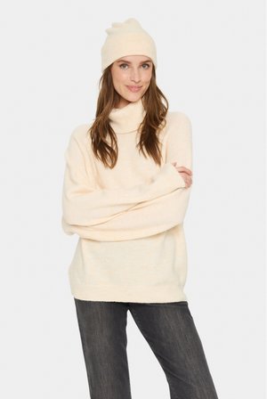 Crème coltrui met een losse pasvorm, ribgebreide manchetten, gecombineerd met een bijpassende beanie. Zachte textuur, lichtgewicht stof, gladde uitstraling.