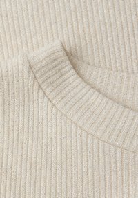 Tessuto di maglione beige a costine con una consistenza morbida. Presenta una leggera lucentezza e un colletto rotondo. Primo piano del motivo a maglia.