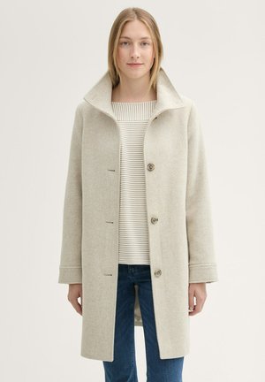 Beige Wollmischungsmantel mit breitem Kragen, vorderen Knöpfen und horizontalen Steppnähten auf der Innenlage, kombiniert mit einem gestreiften Hemd.