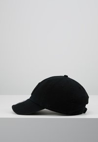 Gorra de béisbol de algodón negra con visera curvada, un logotipo bordado en el lateral y una correa ajustable en la parte posterior.