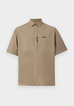 Chemise beige à manches courtes avec col pointu, fermeture éclair frontale invisible et logo "BOSS" sur la poitrine gauche.