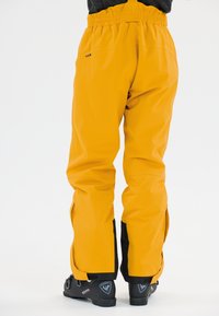 Vedenäni yellow ski pantsit ovat varustettu venyvällä vyötäröosalla, sivutaskuilla ja mustilla yksityiskohdilla lahkeissa, suunniteltu aktiiviseen ulkoilukäyttöön.