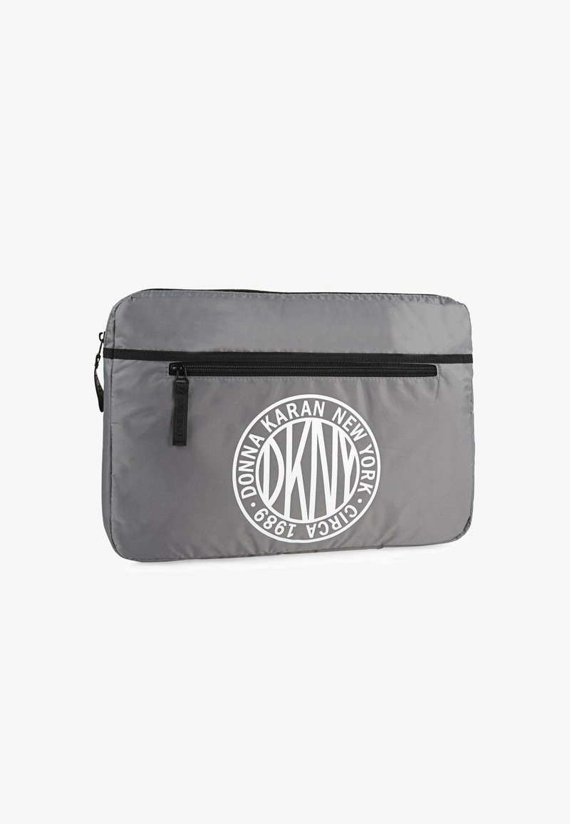 Funda para portátil acolchada en gris con una cremallera negra, que presenta un logotipo circular blanco con el texto "DKNY DONNA KARAN NEW YORK 1984". Textura suave.