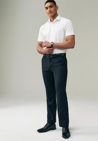 Weißes kurzärmliges Hemd, marineblaue Hose und schwarze Dressschuhe. Schwarzer Gürtel mit silberner Schnalle. Slim-Fit-Design, glatte Textur.