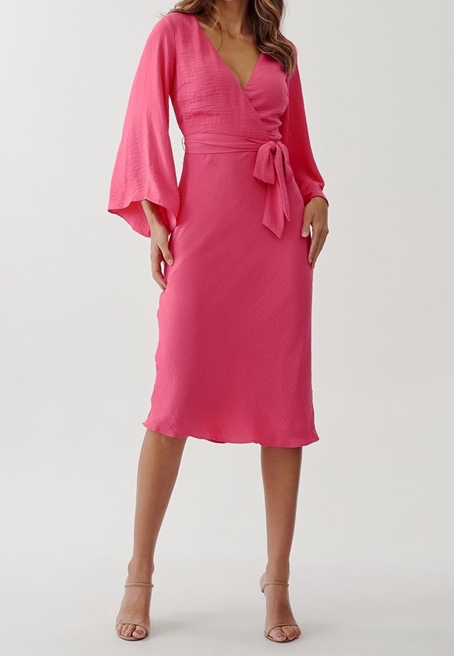 Robe portefeuille rose avec manches cloche longues, tissu texturé, taille cintrée et ceinture nouée à la taille. Silhouette longueur genou.