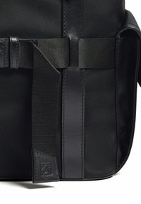 Borsa messenger nera in tessuto con nylon testurizzato, dettagli in pelle liscia e tracolla piatta. Presenta un piccolo tag con logo impresso.