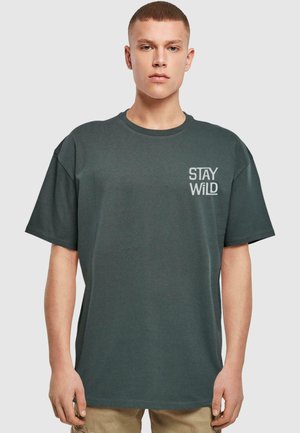 Mørkegrøn kortærmet t-shirt lavet af bomuld, med et hvidt "STAY WILD" tryk på venstre brystområde. Afslappet pasform, rund hals design.