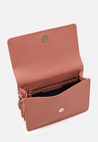 Suorakulmainen vaaleanpunainen teksturoitu käsilaukku, jossa on magneettinen nepparikiinnitys ja vetoketjullinen tasku sisäpuolella. Sisävuori on tummansininen.