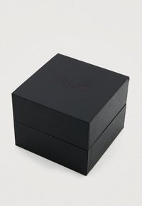 Schwarze rechteckige Schachtel mit strukturierter Oberfläche, auf der der eingeprägte Markenname "LIU·JO" in dunkelrotem Farbton oben zu sehen ist.