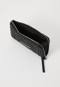 Portefeuille en cuir noir avec un design matelassé, fermeture éclair et plusieurs emplacements pour cartes à l'intérieur. Texture lisse avec un éclat subtil.