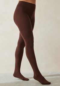 Medias marrones hechas de una tela suave, con un diseño sin costuras que se ajusta a las piernas, con una cintura y área de pies ajustadas.
