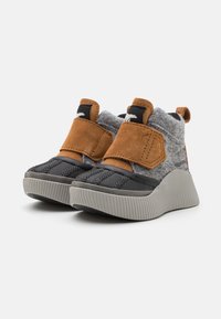 Grå och svarta skor med mjuk grå textil och bruna mocka-accenter, med en kardborreband och en räfflad grå sula.