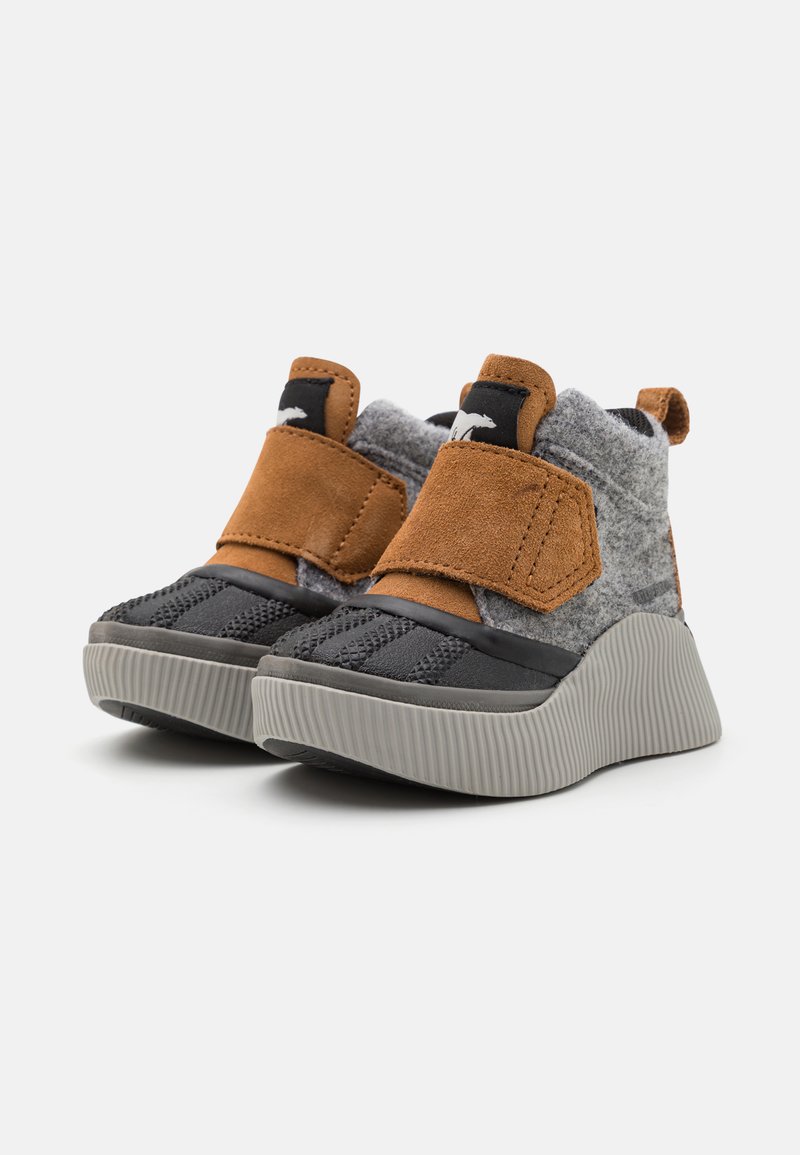 Chaussures grises et noires avec un textile gris doux et des accents en daim marron, dotées d'une bande auto-agrippante et d'une semelle ridée grise.