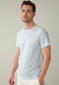 Světle modré tričko s krátkým rukávem, vyrobené z jemného materiálu se decentním pruhovaným vzorem. Obsahuje kulatý výstřih a minimalistický design.