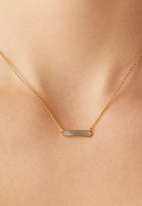 Collier en chaîne en or avec un pendentif rectangulaire à surface texturée, affichant des nuances de clair et de foncé.