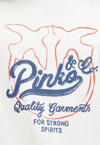 Δύο περιγράμματα πορτοκαλί πουλιών που κοιτάζονται μεταξύ τους πάνω από μπλε κείμενο που γράφει "Pinko & Co. Ποιοτικά ρούχα για δυνατά πνεύματα" σε λευκό ύφασμα.