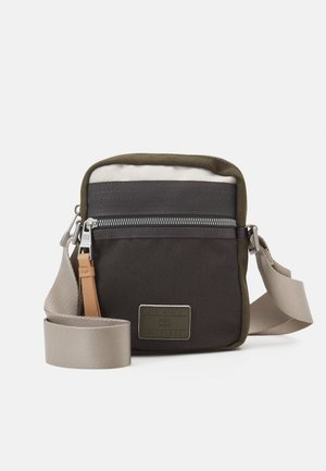 Lille rektangulær crossbody taske med sort og olivengrønt stof, beige justerbar rem, frontlynlåslomme og mærket metalmærke.