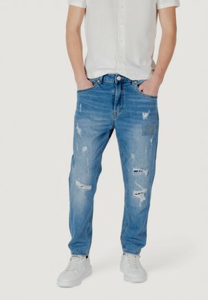 Jeans de mezclilla desgastados de color azul claro con un ajuste relajado, que presentan varias áreas rasgadas y un diseño clásico de cinco bolsillos.