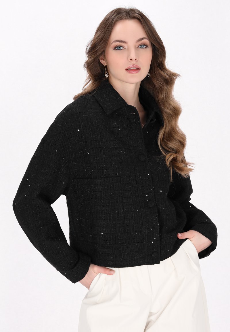 Zwarte cropped jas van gestructureerde stof met een ruitenpatroon, voorzien van een knoopsluiting, twee voorzakken en gespikkelde details.