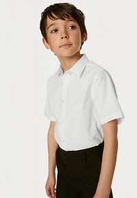 Kortærmet hvid skjorte med knapper, bomuldsmateriale, klassisk krave, glat tekstur, båret med sorte bukser, tætsiddende stil.